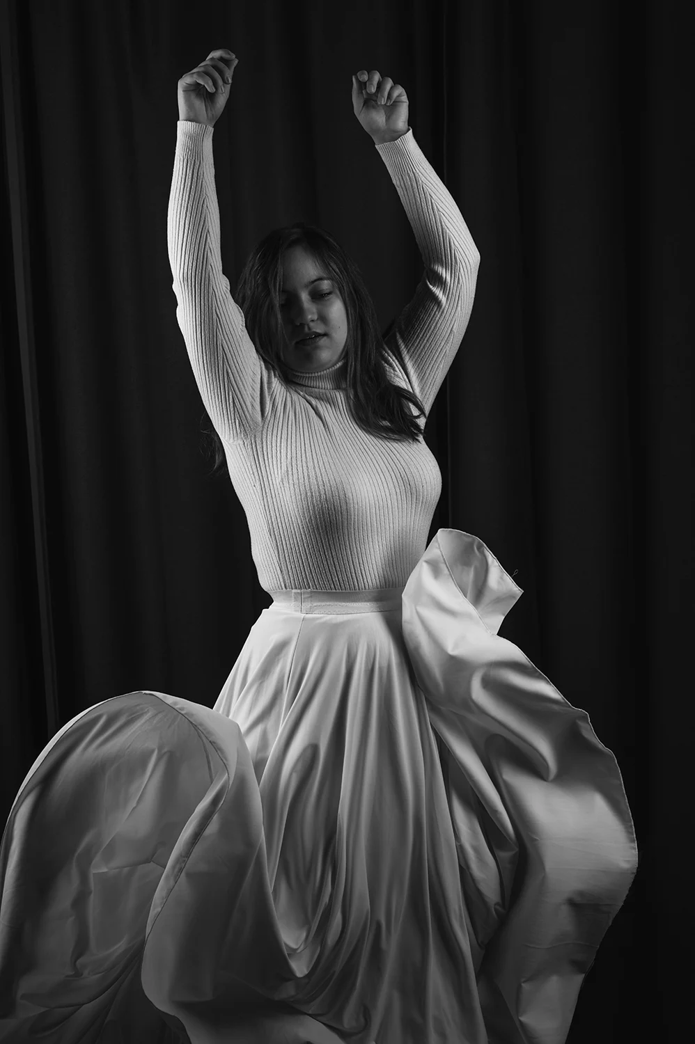Junge Frau trägt ein weißes Kleid, das schwungvoll herunterfällt und dem Bild eine lebendige Dynamik verleiht.